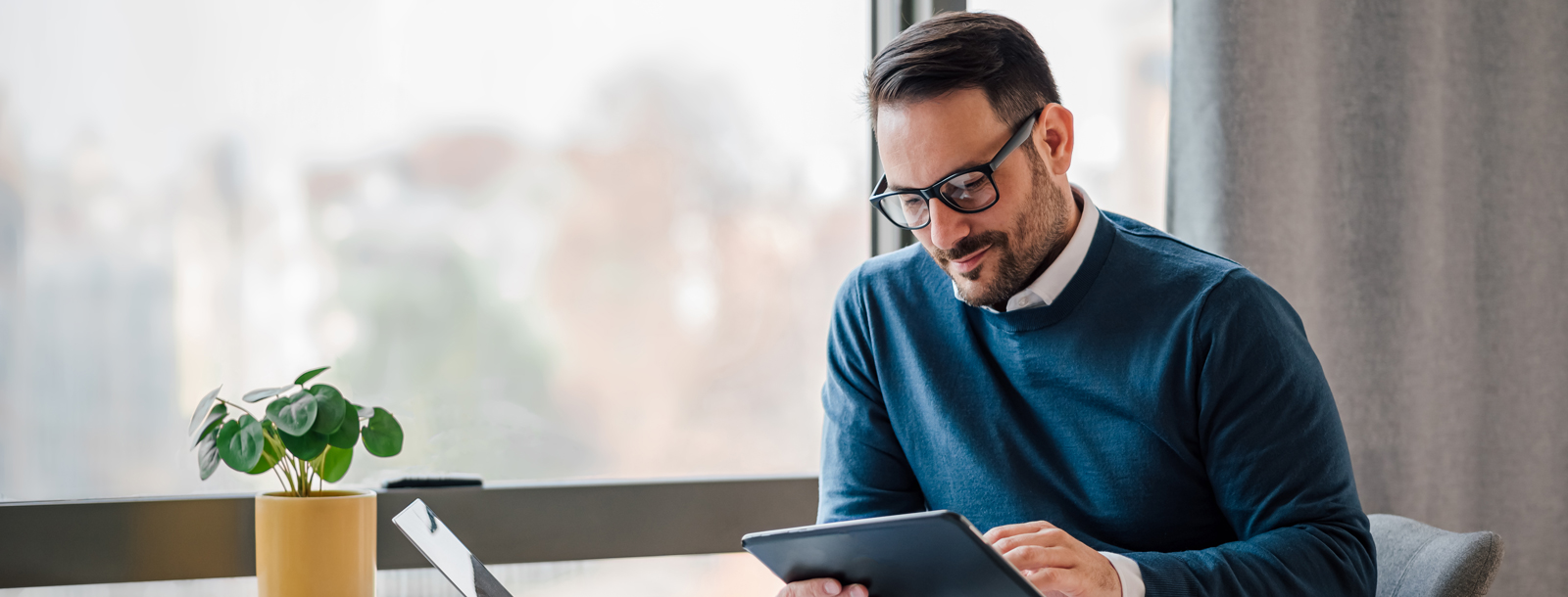 Man in business casual clothing looking at a tablet and smiling