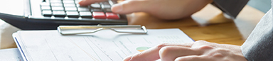 Woman's hands pointing at information on a clipboard and using a calculator