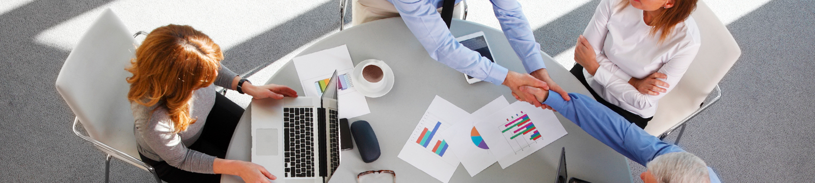 Business people meeting over charts and laptop on table